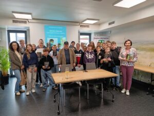 Maciej Sobczak z grupą uczniów i nauczycielkami po spotkaniu autorskim w Gminie Krzymów, dzieci trzymają jego książki