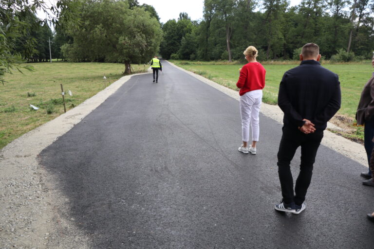 Osoby stojące na nowej nawierzchni asfaltowej drogi w wiejskiej okolicy