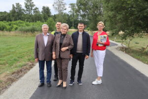 Pięć osób stojących na nowo wybudowanej drodze asfaltowej w otoczeniu zieleni