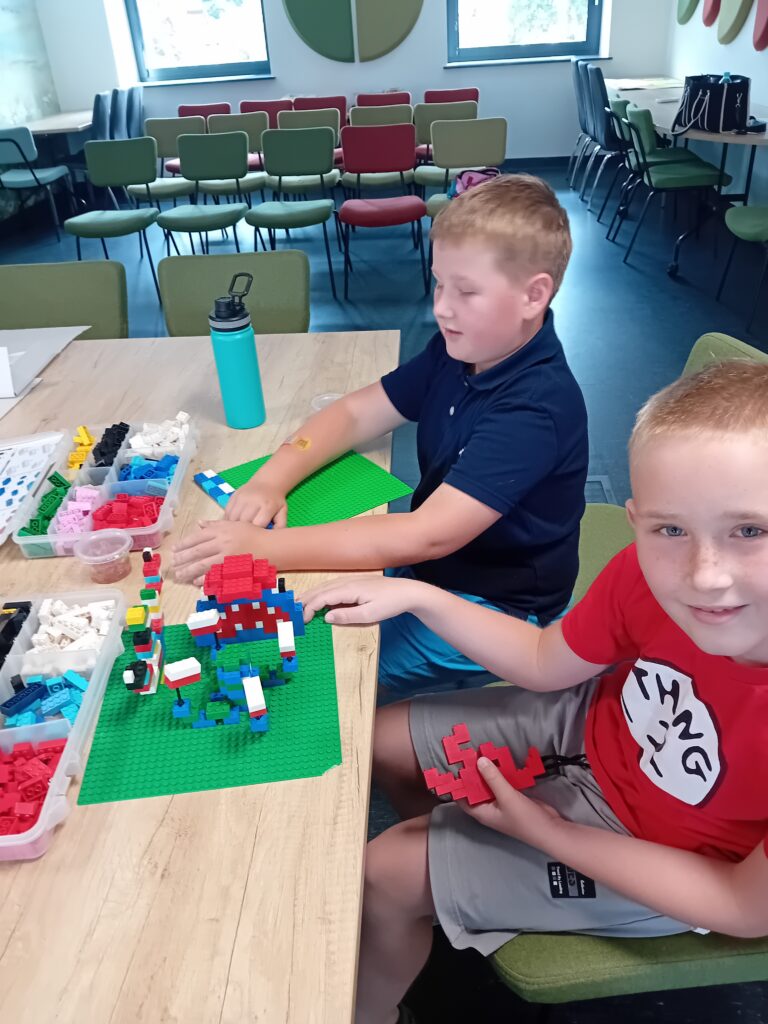 Dwóch chłopców buduje z klocków LEGO przy stole w sali lekcyjnej