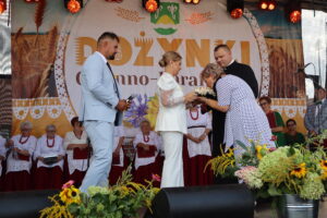 Kobieta całuje chleb dożynkowy wręczany na scenie podczas tradycyjnych dożynek