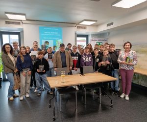Maciej Sobczak z grupą uczniów i nauczycielkami po spotkaniu autorskim w Gminie Krzymów, dzieci trzymają jego książki
