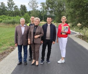 Pięć osób stojących na nowo wybudowanej drodze asfaltowej w otoczeniu zieleni